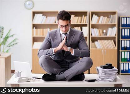 Young businessman meditating in the office