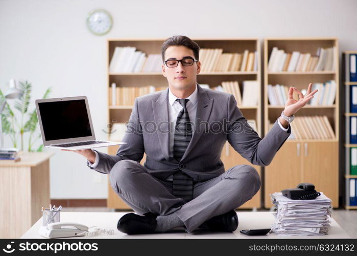 Young businessman meditating in the office