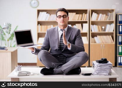 Young businessman meditating in the office