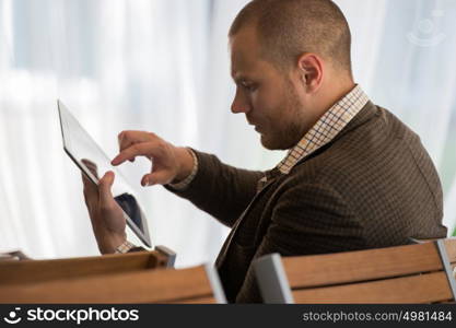 Young businessman on a coffee break. Using tablet computer.