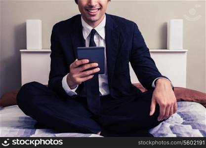 Young businessman on bed reading on tablet
