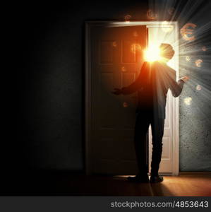 Young businessman opening door. Image of young businessman standing with back opening door against euro sigh background