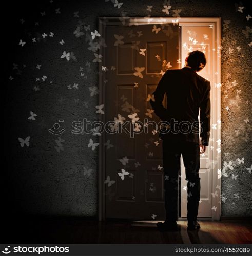 Young businessman opening door. Image of young businessman standing with back opening door