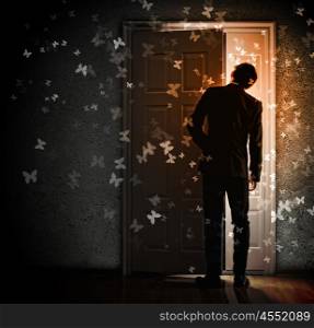 Young businessman opening door. Image of young businessman standing with back opening door