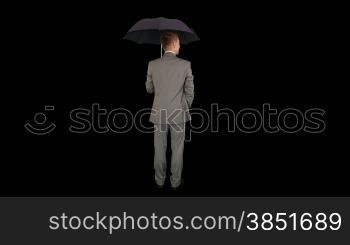 Young businessman opening umbrella, back view, against black