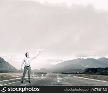 Young businessman outdoor with paper plane in hand