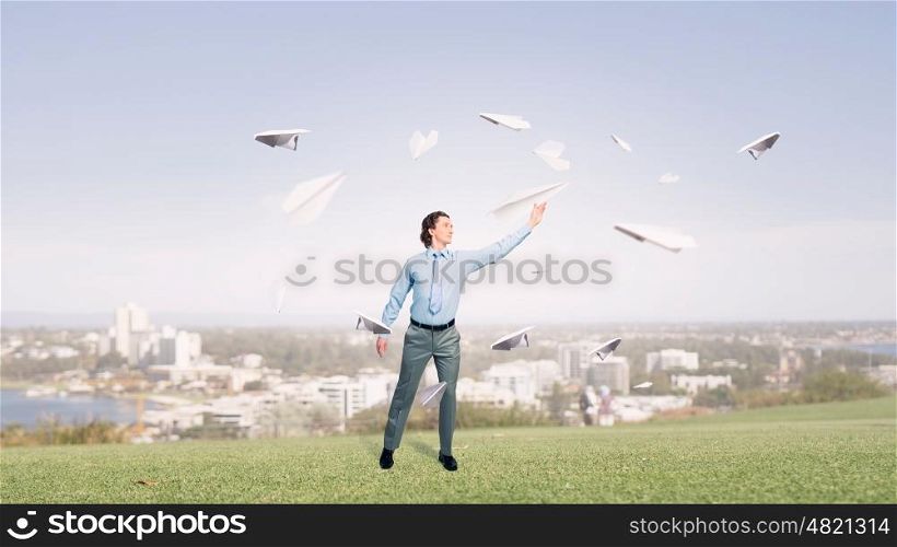 Young businessman outdoor with paper plane in hand