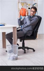 Young businessman playing basketball in office during break