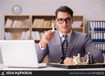 Young businessman playing chess in the office