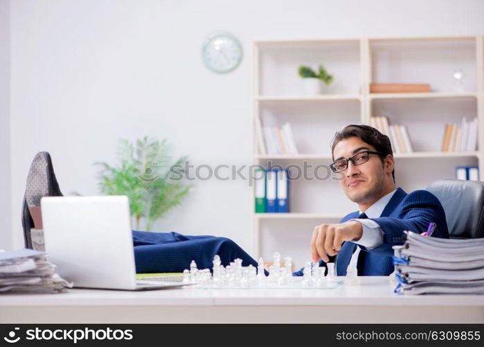 Young businessman playing glass chess in office