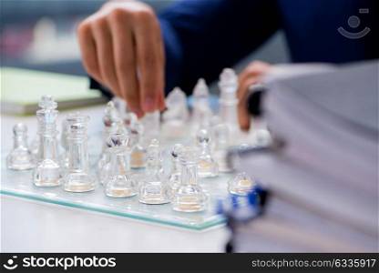 Young businessman playing glass chess in office