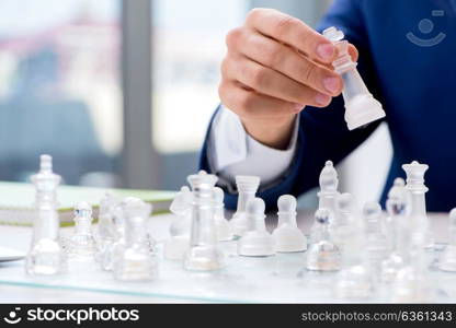 Young businessman playing glass chess in office