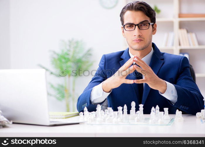 Young businessman playing glass chess in office