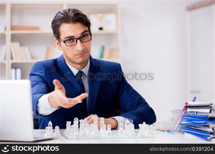 Young businessman playing glass chess in office