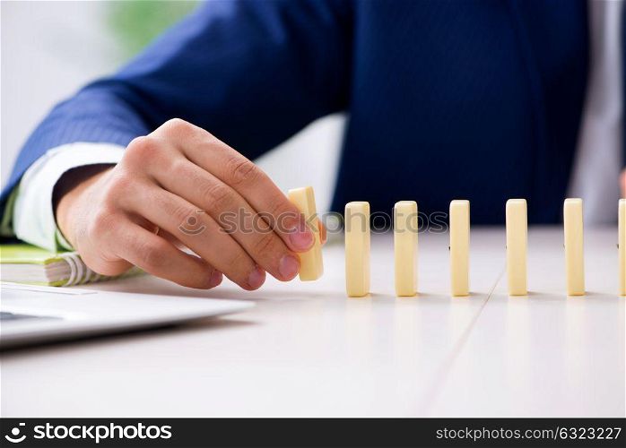 Young businessman playing with domino in office