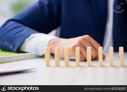 Young businessman playing with domino in office