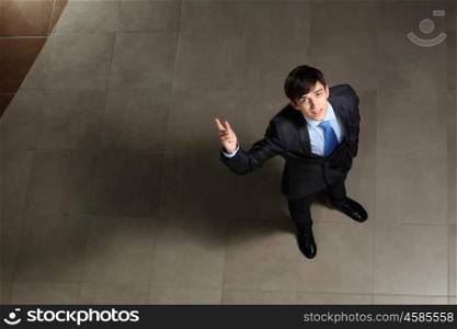 Young businessman pointing with finger. Image of young businessman pointing with his finger up. Top view