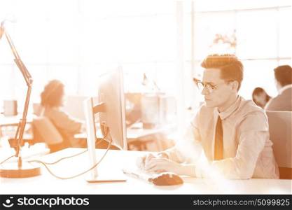 Young businessman programer in big bright office at work using computer