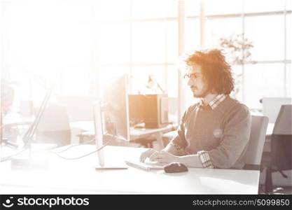 Young businessman programer in big bright office at work using computer