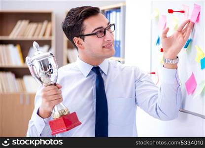 Young businessman receiving prize cup in office