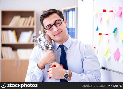 Young businessman receiving prize cup in office