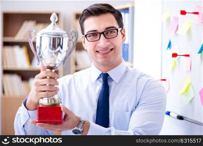 Young businessman receiving prize cup in office
