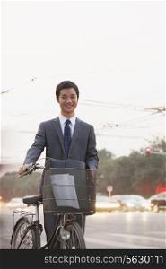 Young businessman riding a bicycle on the street, Beijing, portrait