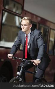 Young businessman riding bicycle by bus