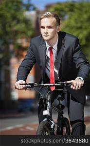 Young businessman riding bicycle on street
