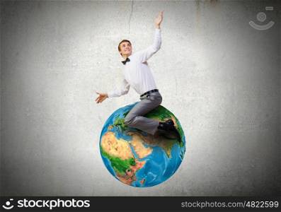 Young businessman riding Earth planet. Elements of this image are furnished by NASA. Riding Earth planet