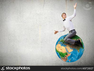 Young businessman riding Earth planet. Elements of this image are furnished by NASA. Riding Earth planet