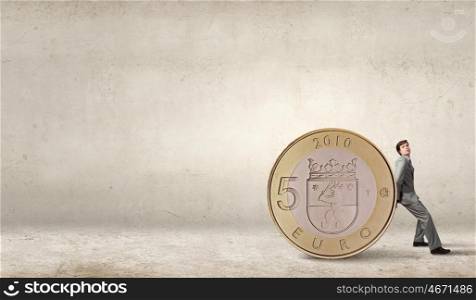 Young businessman rolling huge five euro coin. Man and big coin