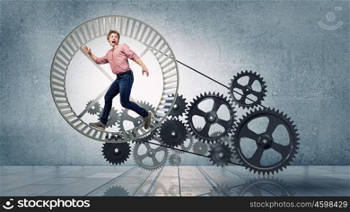 Young businessman running in wheel of gears mechanism. To turn as squirrel in wheel