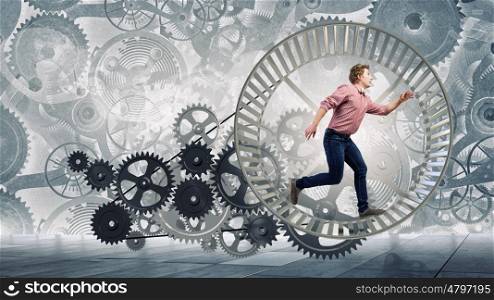 Young businessman running in wheel of gears mechanism. To turn as squirrel in wheel