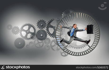 Young businessman running in wheel of gears mechanism. To turn as squirrel in wheel