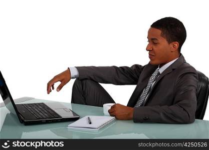 Young businessman sat at laptop with coffee in hand