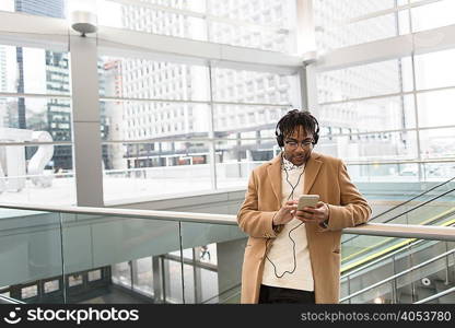 Young businessman selecting smartphone music in train station