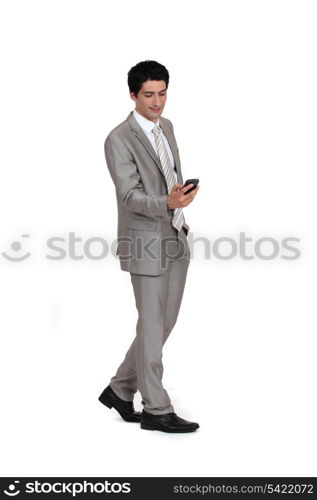 Young businessman sending text message whilst walking