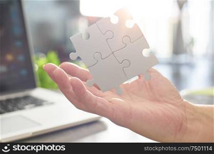 Young businessman showing puzzle partnership puzzle piece with sun flare and blur background,symbol of association and connection. business strategy.