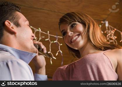 Young businessman singing to woman at local bar, night