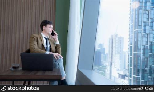Young businessman sit and relax in the relaxation room by the window overlooking the beautiful city buildings. along with the phone to talk about business.