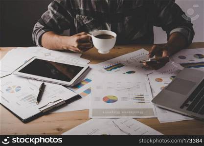 Young businessman sitting and using mobile phone at workplace in. Young businessman sitting and using mobile phone at workplace in office. Business man take a break while working analysis with business data.
