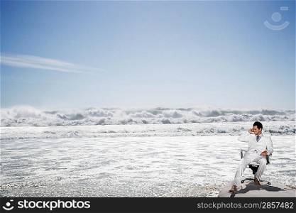 Young Businessman Sitting in an Office Chair at the Beach
