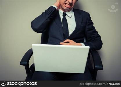 Young businessman sitting in an office chair has a sore neck