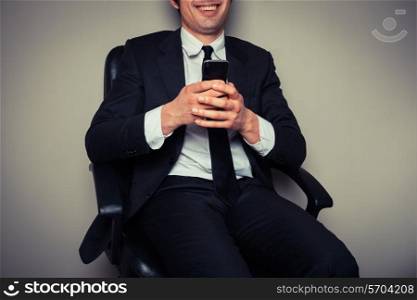 Young businessman sitting in an office chair is using his smart phone