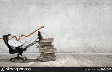Young businessman sitting in chair with old book in hands. Education advantage