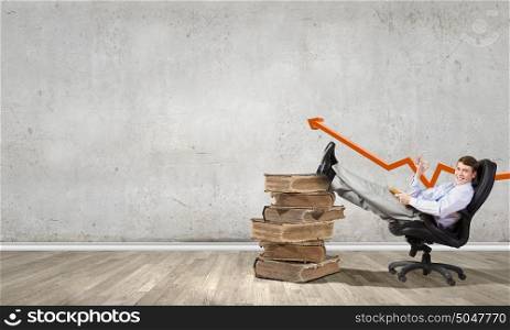 Young businessman sitting in chair with old book in hands. Education advantage