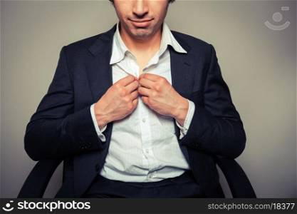 Young businessman sitting in office chair is buttoning his shirt