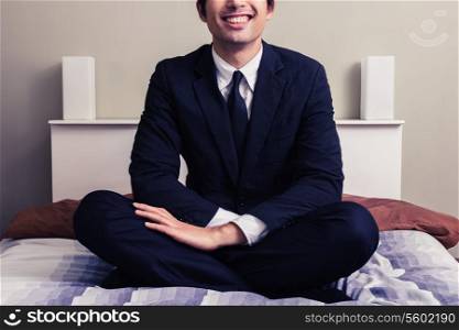 Young businessman sitting on a bed in hotel room