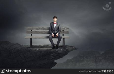 Young businessman sitting on bench with glasses in hands. Businessman on bench